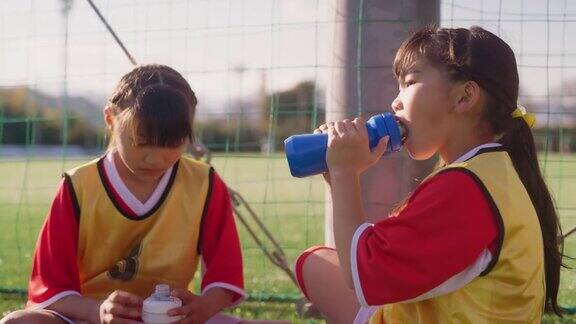 图为在训练过程中两名女足队员一边聊天一边喝着水休息