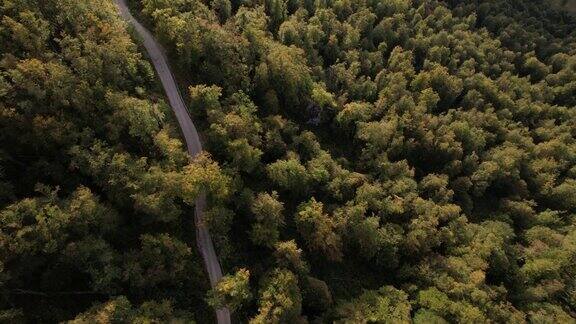 一辆灰色的汽车行驶在穿过山区的空旷道路上