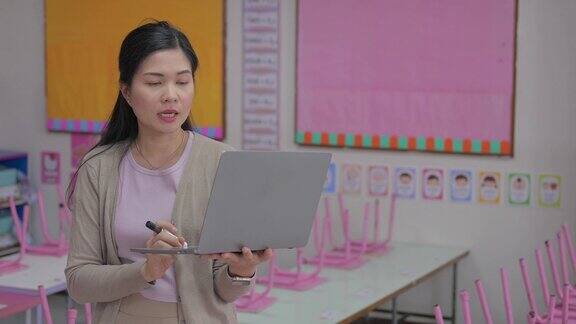 年轻的亚裔女老师在学校的白板上写字在学校的课堂上教学生