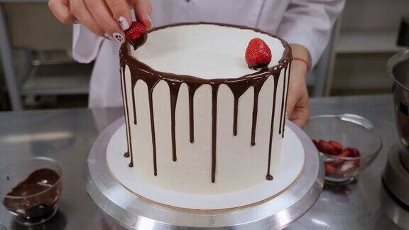 一个女人把巧克力草莓放在一个有白色奶油的蛋糕上