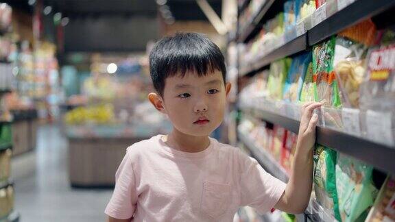一个亚洲小男孩在超市买零食