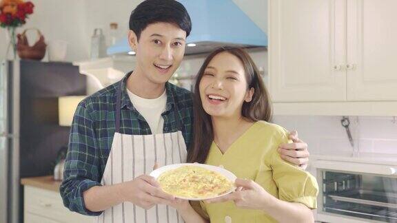 描绘一对相爱的年轻夫妇在家里帮助做饭在浪漫的气氛中微笑着看着镜头