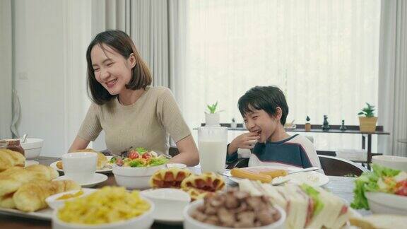 小可爱的儿子喜欢在早上和他年轻漂亮的妈妈一起吃饭6岁的儿子上学前和亚洲妈妈在餐厅吃早餐花时间陪妈妈