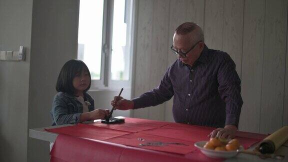 亚洲华裔年轻女孩帮助和学习她的祖父写中国书法