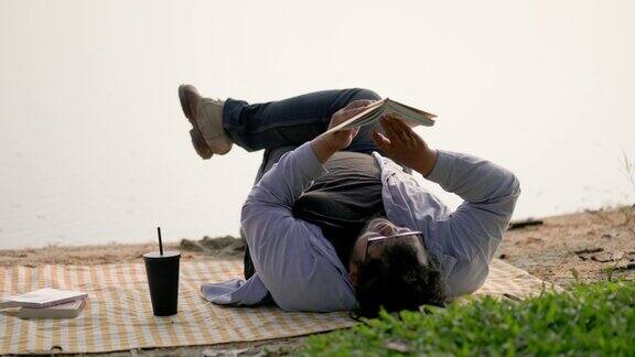 躺在野餐毯子上的男人在海滩上看书