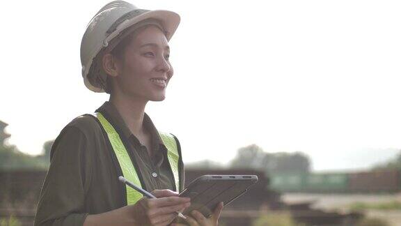 工业工程师亚洲女性戴安全帽穿安全夹克使用触摸屏平板电脑
