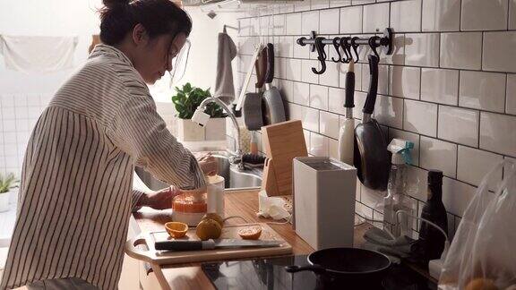 年轻女子在厨房柜台用榨汁机压榨橙子