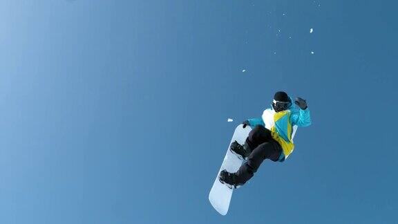 慢镜头:一名男性游客从空中飞过表演滑雪特技