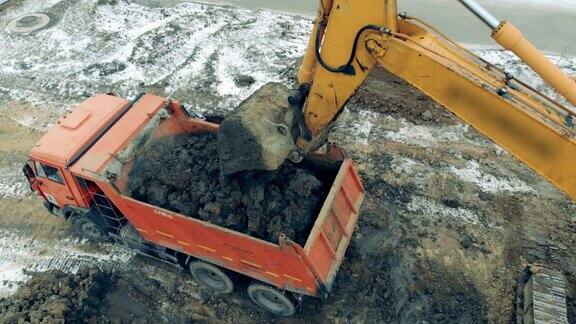 一个建筑挖土机装载一辆卡车沙子和石头