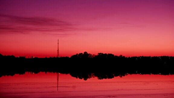 日落时河边树木和高塔的剪影
