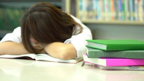 亚洲女学生一边睡觉一边醒来在学校图书馆看书