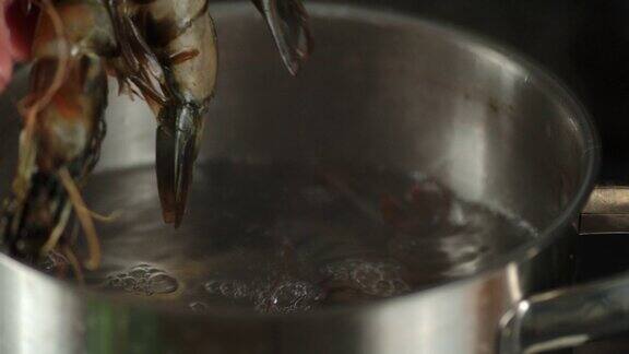 男子的手将生虾放入锅中的沸水中