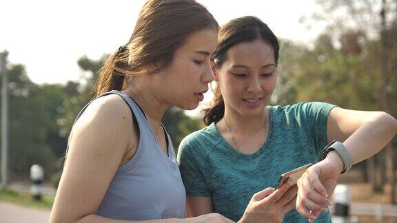 亚洲女性看智能手表与朋友锻炼的数据