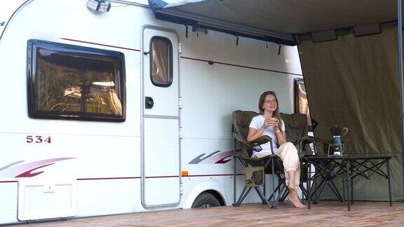 微笑的女人有乐趣在户外露营与露营拖车房车