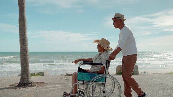 老年夫妇老年男子带着老年妇女坐在轮椅上在海边放松保健理念夫妻关系