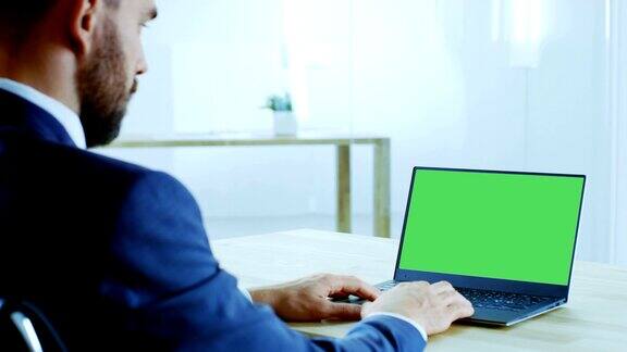 可敬的商人工作的笔记本电脑与隔离模型绿色屏幕他的办公室既明亮又现代化