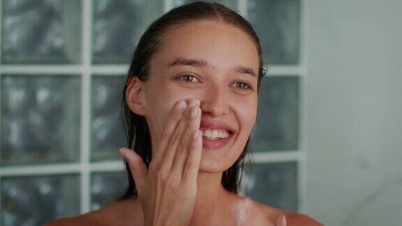 快乐女人在浴室用保湿霜护肤