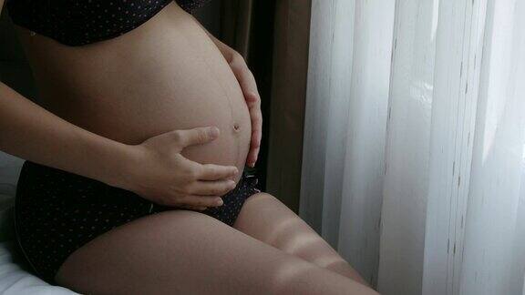 孕妇抚摸并展示她的腹部