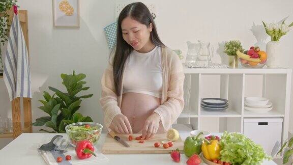 快乐的亚洲孕妇在家里做沙拉做新鲜的蔬菜沙拉怀孕期间吃很多不同的蔬菜健康的怀孕理念