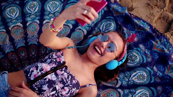 年轻女子戴着耳机在海滩上听音乐