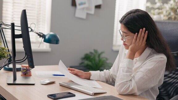 穿着白衬衫的漂亮办公室秘书坐在电脑显示器前她累了想睡觉用手撑着脸等待工作结束