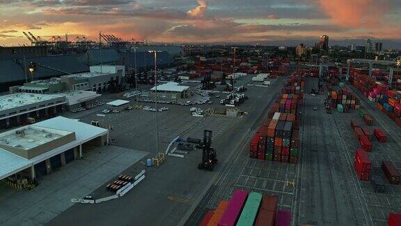 日落时分停在集装箱堆场的卡车和搬运工
