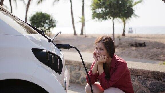 无聊的亚洲女人等着电动汽车充电