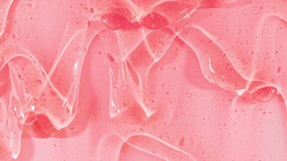 粉色透明化妆品凝胶液与分子气泡流动在平坦的白色表面微距镜头