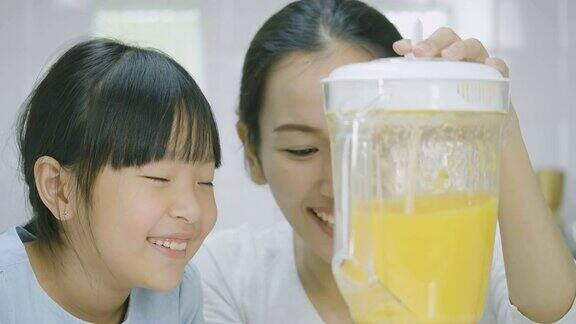 一名孕妇和她的女儿在搅拌机里搅拌水果奶昔