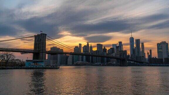 4K时间推移下曼哈顿金融区城市景观河岸与布鲁克林大桥在日落时间和白天到夜晚的场景美国纽约建筑和地标概念