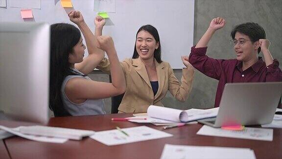 一群亚洲年轻的商业女性或办公室女性使用电脑在现代办公室一起讨论工作快乐和成功的情绪概念的4k视频慢镜头
