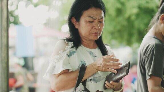 一位泰国老妇人正在泰国当地市场购买食物和蔬菜
