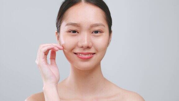 肖像年轻的亚洲美女触摸健康的面部美皮肤超过灰色的背景亚洲美皮肤