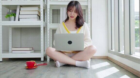 亚洲女性在客厅的地板上用笔记本电脑工作家庭办公室社交距离