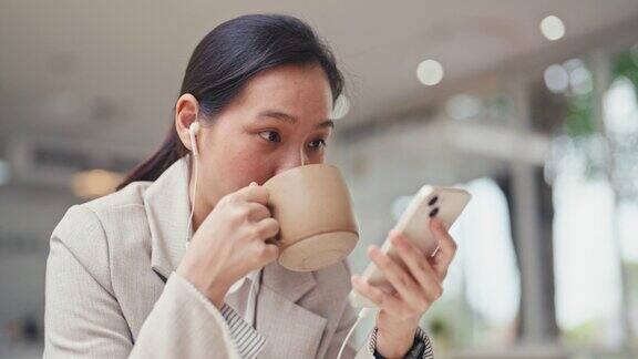 亚洲女性一边拿着咖啡杯一边用手机