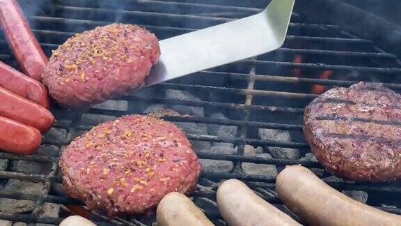 夏天在后院烧烤时用厨房的金属铲翻转多汁的汉堡包调味碎牛肉热狗烤肠