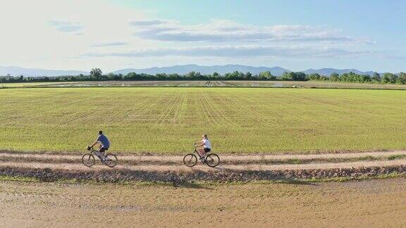 一对夫妇在农村骑自行车的侧视图视频
