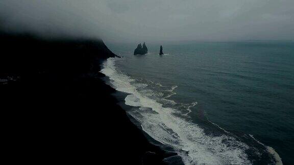 鸟瞰图的黑色火山海滩在冰岛和巨怪脚趾的岩石在海里直升机在浪花上飞