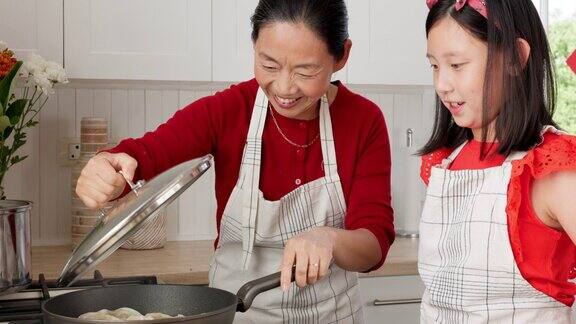 亚洲家庭妈妈和孩子在炉子上用平底锅煮饺子作为午餐晚餐和传统食物快乐的孩子在厨房里帮助妈妈学习中餐、文化和食谱