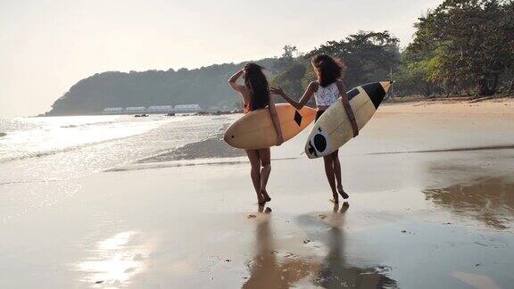 亚洲两个美丽的年轻女子冲浪女孩在沙滩上穿着比基尼和白色冲浪板体育cinemagraph