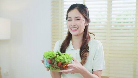 微笑的漂亮女人在厨房里拿着健康的沙拉