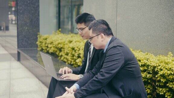 两个亚洲商人在街上使用笔记本电脑