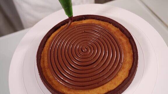 厨师将美味的巧克力奶油放在蛋糕顶的架子上
