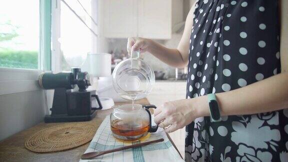 女人的手在厨房的桌子上倒茶