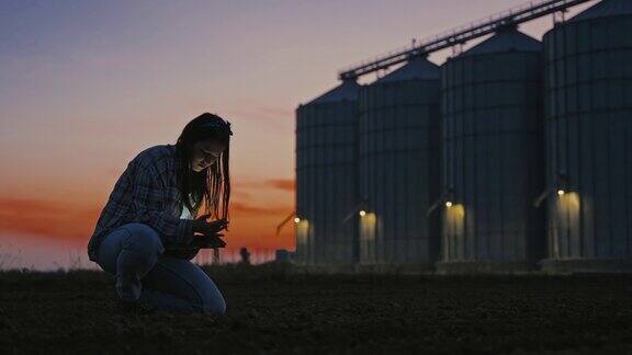 青年女农民黄昏时分在玉米仓旁测土测片