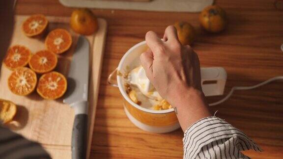 年轻女子在厨房柜台用榨汁机压榨橙子