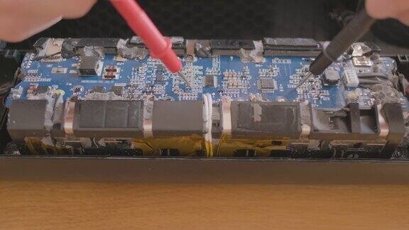 手握工程师用多路测试仪检查接触微电路电池管理板特写拆卸的微控制器微芯片维修车间
