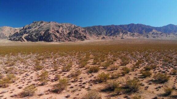 卡车前进无人机拍摄的一个沙漠平原在犹他州与山脉背景下的晴朗蓝天