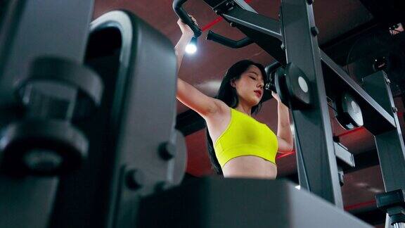 美女在健身中心做引体向上运动年轻的亚洲妇女穿着运动服在健身房锻炼