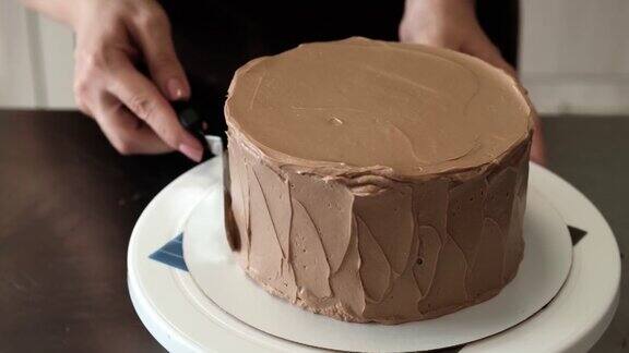 4K女糕点厨师在巧克力蛋糕上抹巧克力奶油特写镜头缓慢的运动蛋糕制作过程